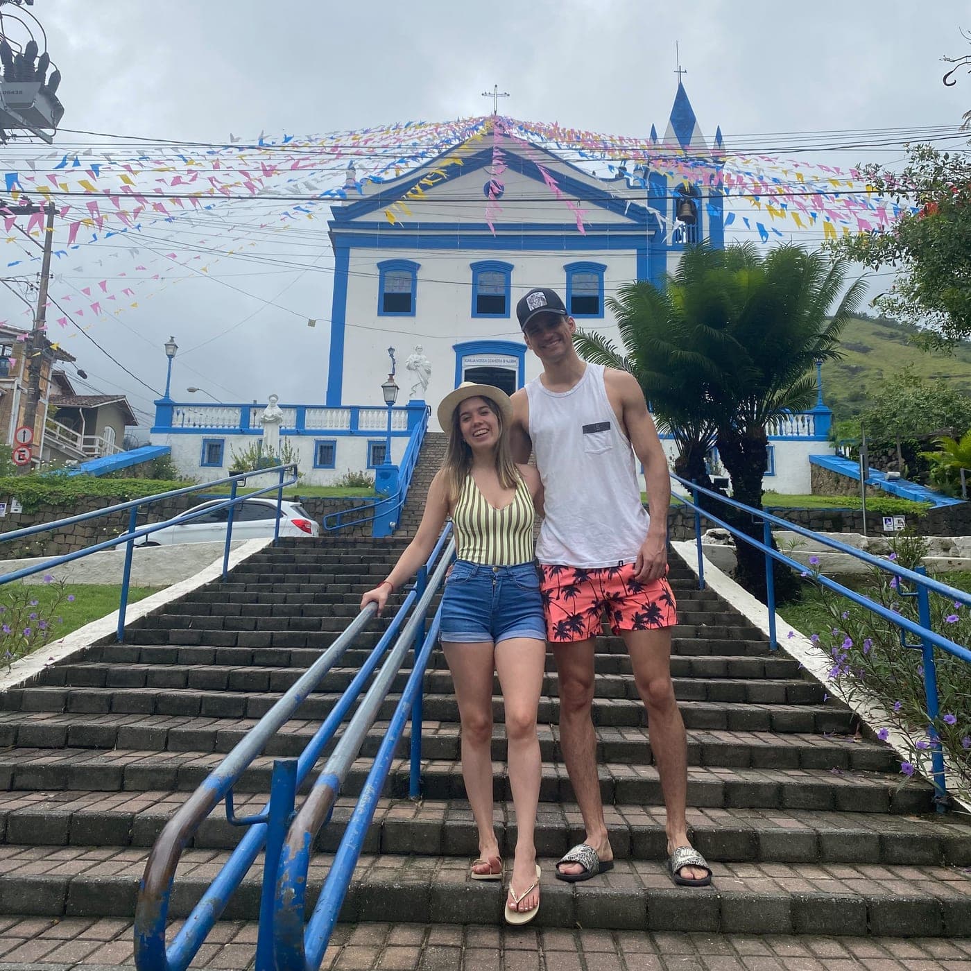 Caro y Valen al pie de una escalinata, frente a una iglesia blanca y azul con banderines