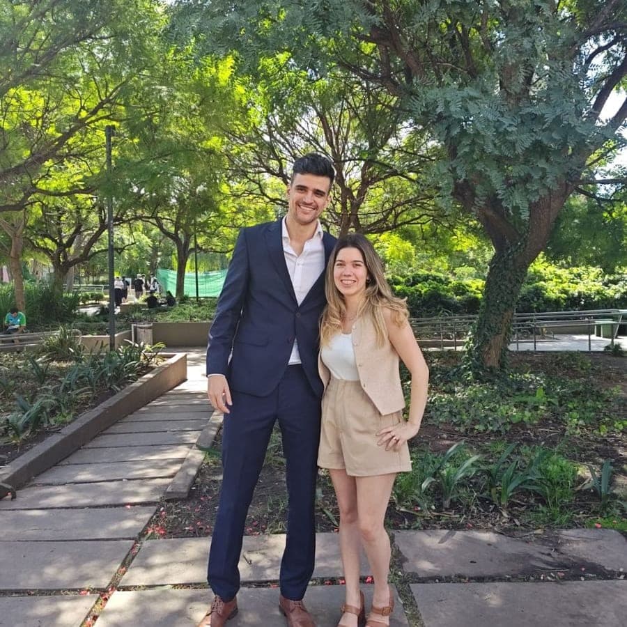 Caro y Valen vestidos de fiesta en un sendero de un parque, entre árboles